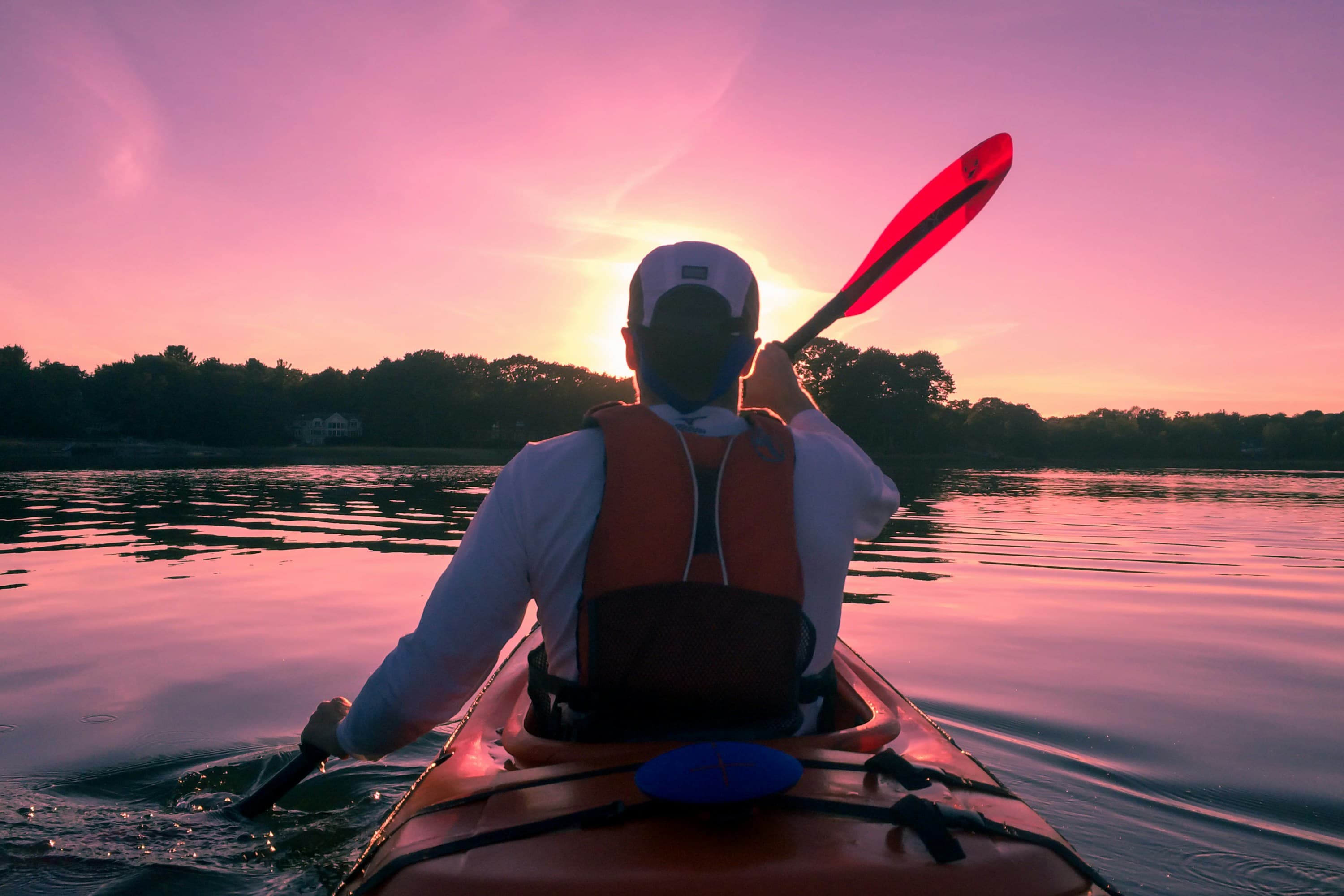 Kayaking at sunset on a tree-lined river